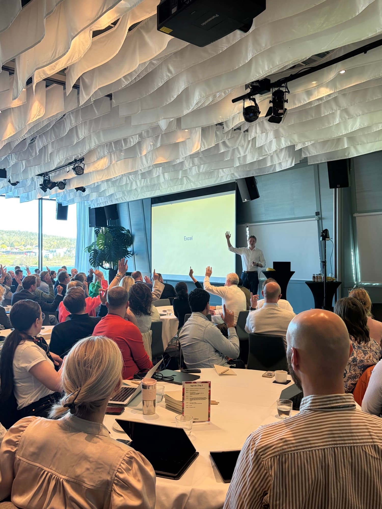 A full room with hands in the air during a workshop session