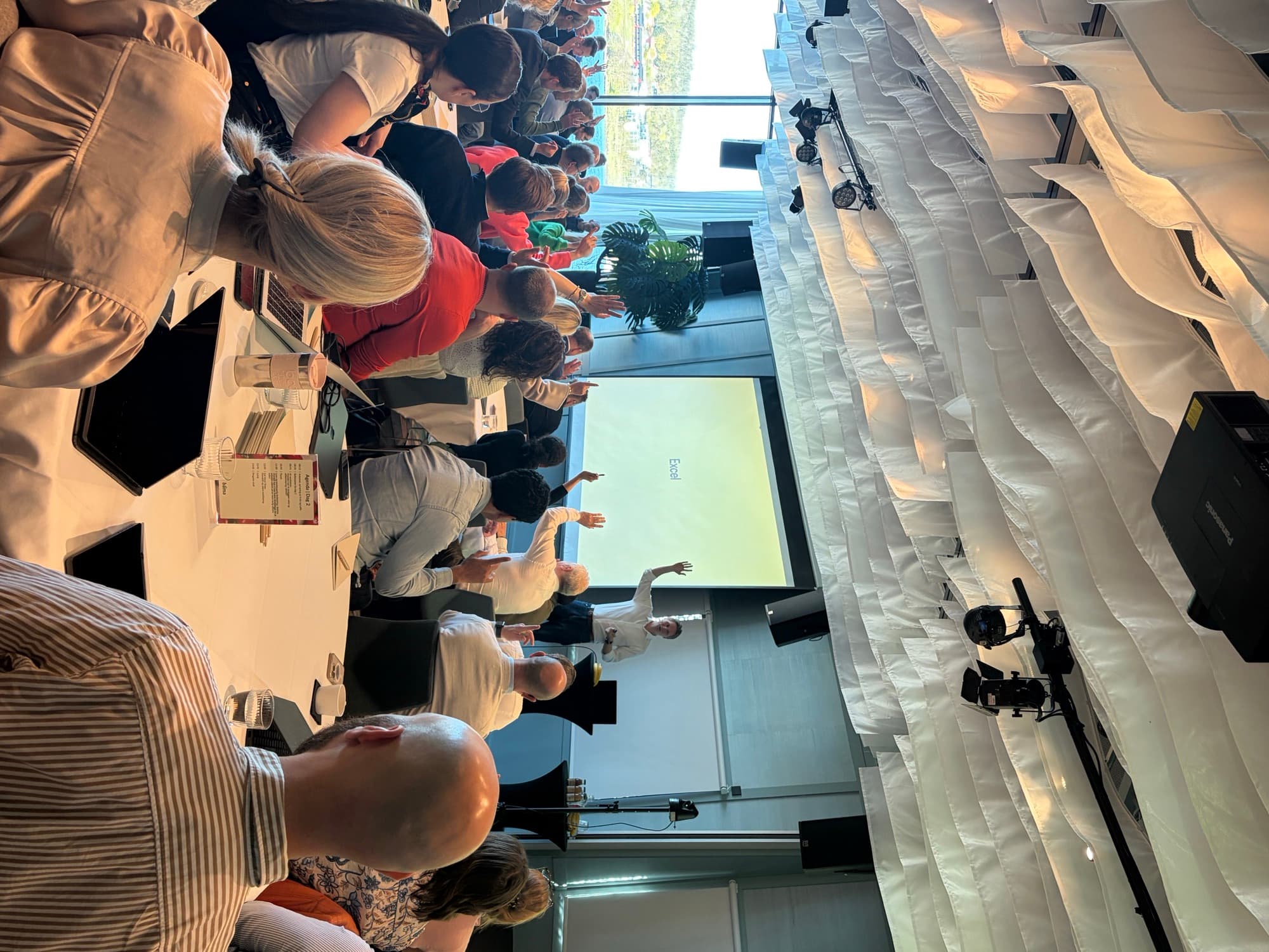 A full room with hands in the air during a workshop session